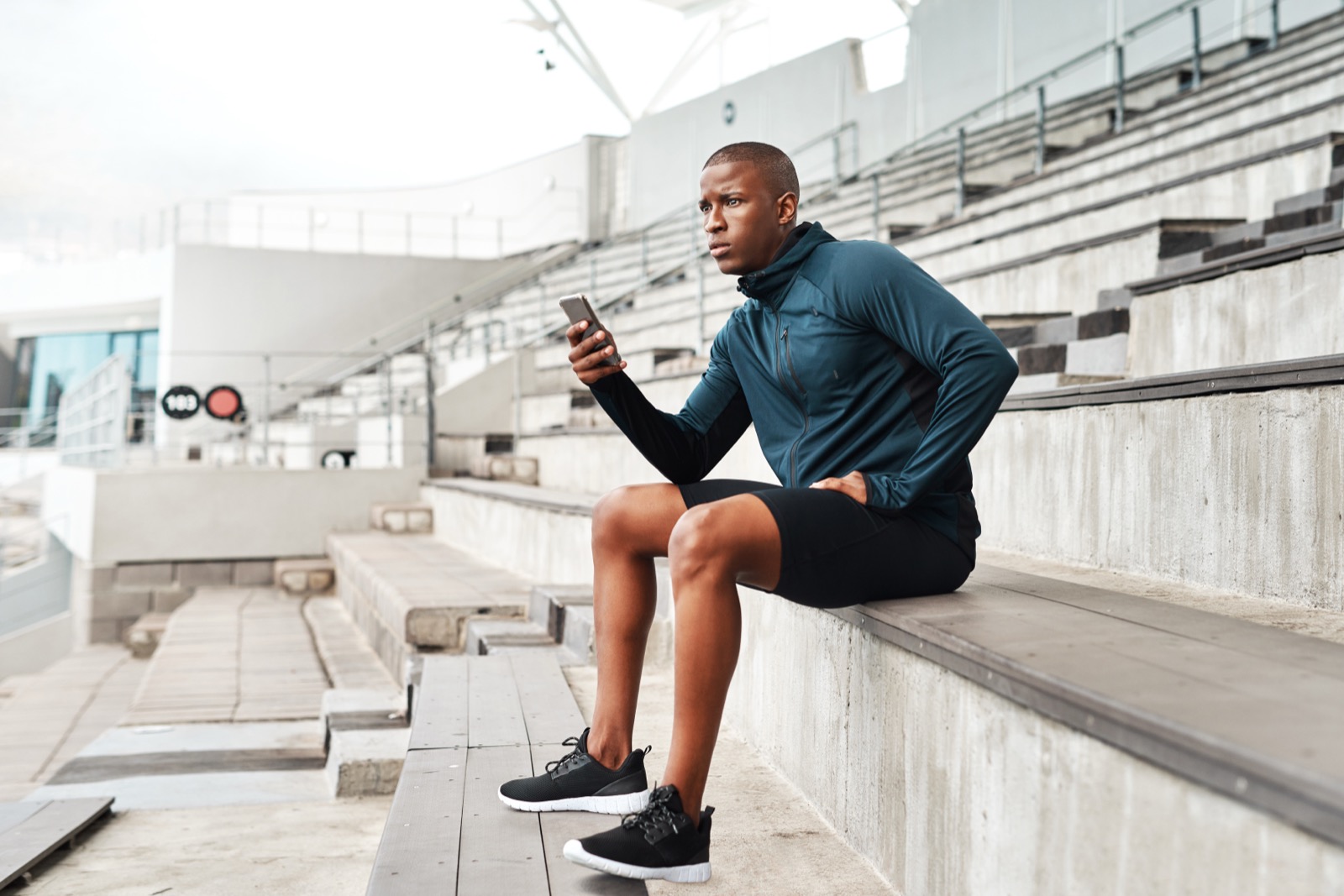 A young athlete completing a two-minute check-in on his phone in the stadium stands after practice